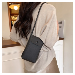 Detail of black pebbled leather crossbody bag with flap closure and slim strap