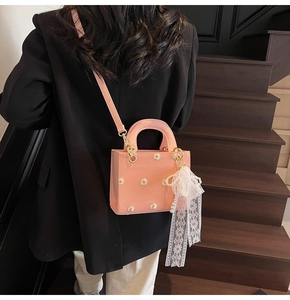 Detail shot of a pink mini handbag with daisy embroidery and a pearl lace charm
