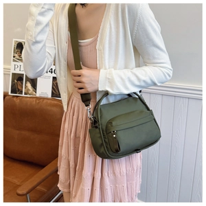 Detail of army green nylon crossbody bag showing the wide strap and metal hardware