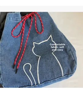 Close-up of denim tote with white cat embroidery and red-white striped drawstring