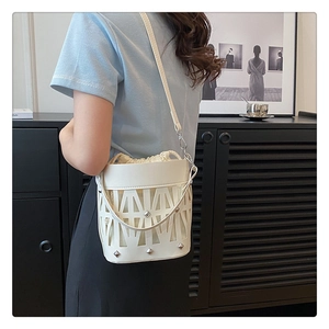 Detail of white hollowed-out bucket bag with geometric triangles and inner drawstring pouch