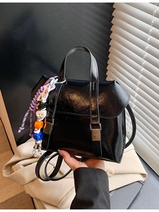 Chic black glossy bucket backpack for women featuring stylish metal buckles and charm