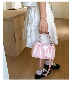 Detail of pink pleated bucket bag featuring elegant bead handle and satin-like texture