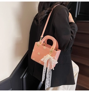 Pink lady bag with daisy print and lace pearl bow charm shown as cross-body style