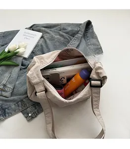 Top view of spacious interior of a beige nylon shoulder bag holding daily essentials
