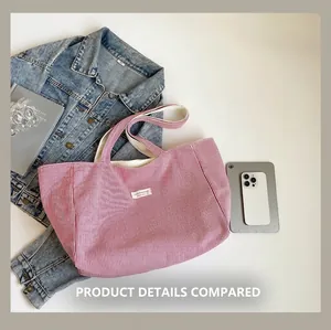 Détail du sac cabas en toile rayée rouge avec étiquette brodée près d'un smartphone