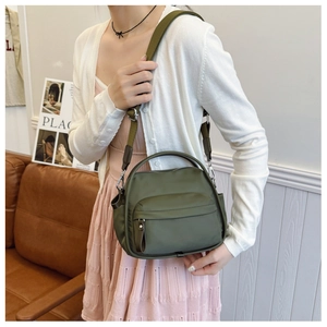 Olive green crossbody bag with adjustable wide strap worn by a model in a casual setting