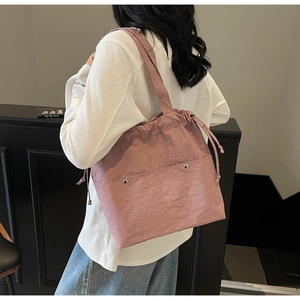 Detail of dusty pink drawstring tote bag in waterproof nylon fabric on a model