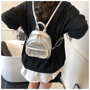 Nahaufnahme des silbernen Mini-Rucksacks mit Schleife und Spitze am Modell