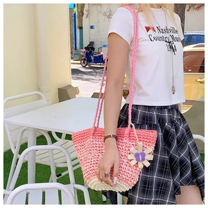 Detail of pink and white gradient straw bag with woven strap and flower charm accessory