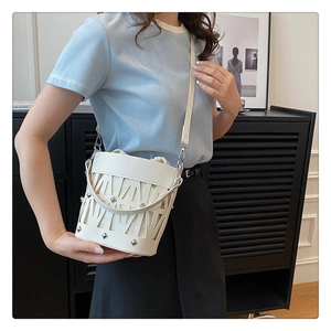 Detail of white hollow-out bucket bag featuring silver rivets and drawstring liner