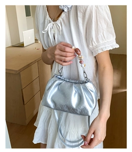 Detail of silver pleated cloud bag featuring marble beads handle and smooth metallic finish