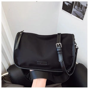 Détails du sac bandoulière noir en nylon minimaliste avec sangle large et logo en métal