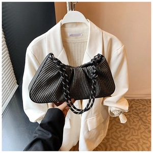 Detail of black and white woven pleated handbag with thick rope shoulder strap in a hand