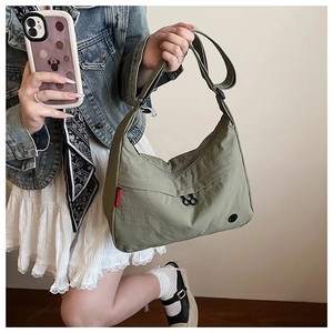 Detail of green nylon crossbody bag showing the adjustable strap and zipper closure
