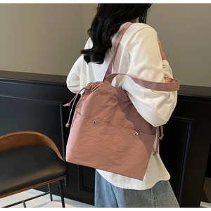 Detailed close-up of pink nylon drawstring tote bag with silver snap button pocket