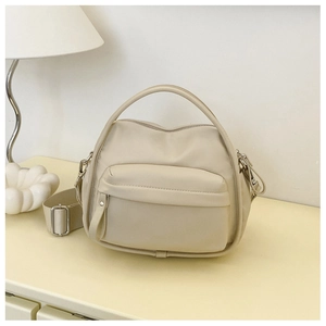 Detail of a beige crossbody bag with adjustable strap and front zipper pocket