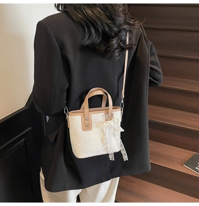 Schicke cremefarbene und braune Beuteltasche mit Spitzenschleife am Modell im Stadtstil