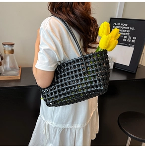 Close-up of black woven hollow tote bag with intricate texture and sleek leather straps