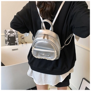 Detailansicht eines silbernen Mini-Rucksacks mit Schleife und Spitze am Modell