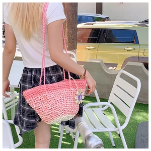 Detail of pink and beige gradient straw bag with woven straps and flower charm