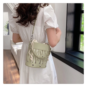 Detail of light green hollow-out bucket bag with silver studs and white drawstring liner
