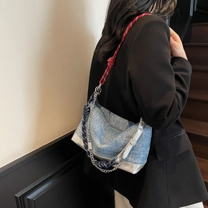 Detail of blue denim tote bag with thick rope straps and metallic silver trim on shoulder