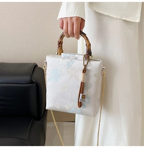 Detail of floral embroidery on a retro bag with natural bamboo handle and gold chain strap