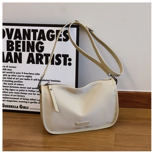 Détail d'un sac bandoulière crème minimaliste avec sangle réglable et logo métal