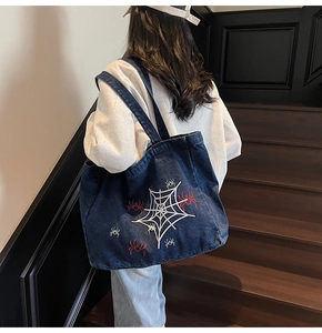 Detail of navy denim tote bag with white spider web and red spider embroidery on stairs