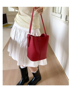 Detail of red lychee pattern bucket bag with silver side buckles and embossed logo