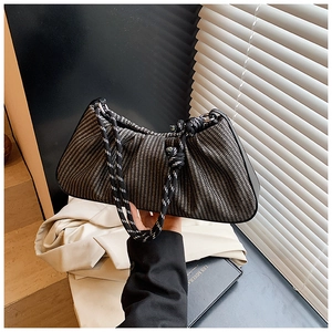 Close-up of retro woven baguette bag featuring black and white rope handle and metal rings