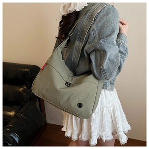 Detail view of the sage green nylon crossbody bag with textured fabric and red tag