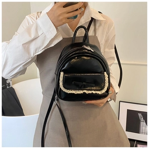 Detail eines schwarzen Mini-Rucksacks aus PU-Leder mit weißer Spitze und Schleife