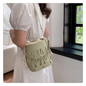 Detailed close-up of light green cutout bucket bag with silver studs and canvas drawstring
