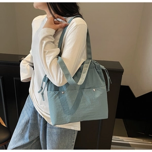 Side view of large light blue nylon tote bag with drawstring closure worn by a model
