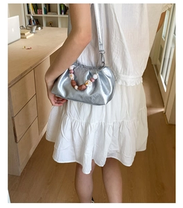 Detail of silver metallic pleated bucket bag with colorful beaded handle and shoulder strap