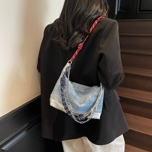 Detail of vintage blue denim tote bag with red-white braided ropes and silver chain