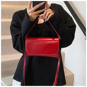 Rode glanzende leren flap tas gecombineerd met een zwarte outfit voor een chique look