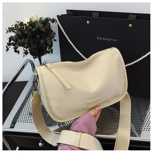 Gros plan du sac oreiller en toile crème avec bandoulière large et pompon