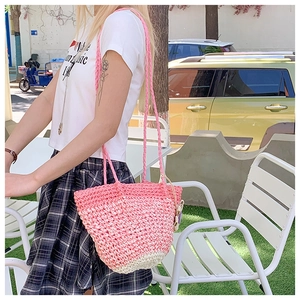 Detail of pink and white gradient straw shoulder bag worn by model in outdoor street setting