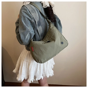 Olive green nylon crossbody bag shown from a side view on a model for daily use