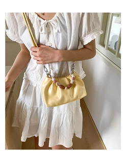 Close-up of pleated bucket bag with decorative pearl beads handle and soft yellow finish