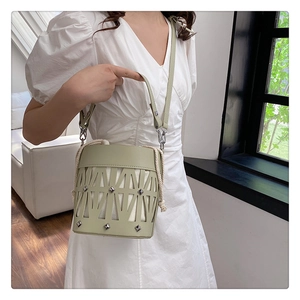 Detail of green hollow bucket bag featuring silver rivets and white drawstring inner pouch