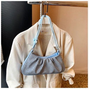 Detail of woven texture and knot handle on a stylish blue and white pleated shoulder bag