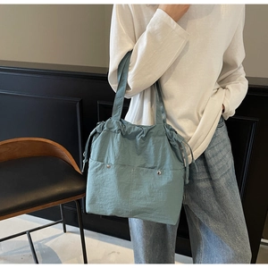 Detail view of morandi blue drawstring bucket bag with silver snap button front pockets