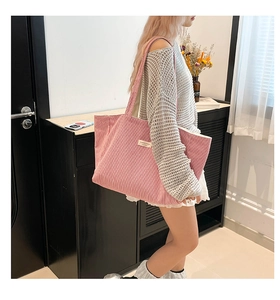 Détail du sac cabas en velours côtelé rose montrant la texture fine et l'étiquette en tissu