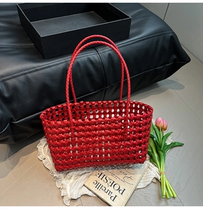 Close-up of a red woven tote bag with cutout leather texture and slender double handles