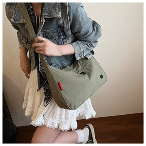 Detail of army green large nylon crossbody bag with red label and durable wide shoulder strap