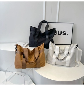 Three travel tote bags in black, tan, and cream shown with side buckle detail
